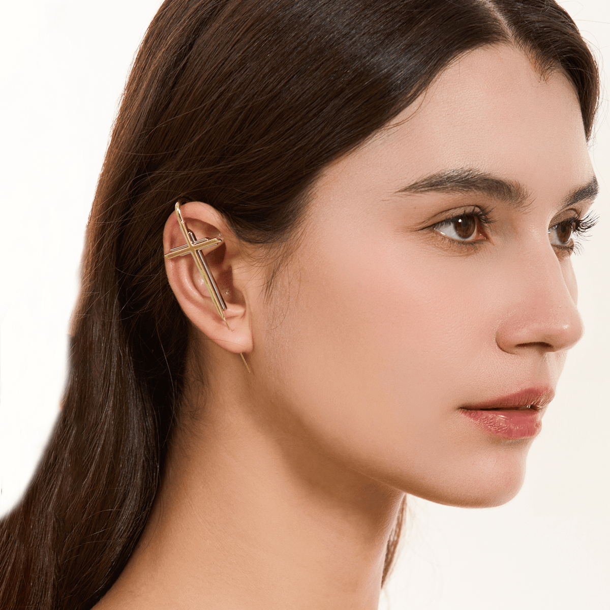 Cross ear cuff in gold worn on the ear, profile view
