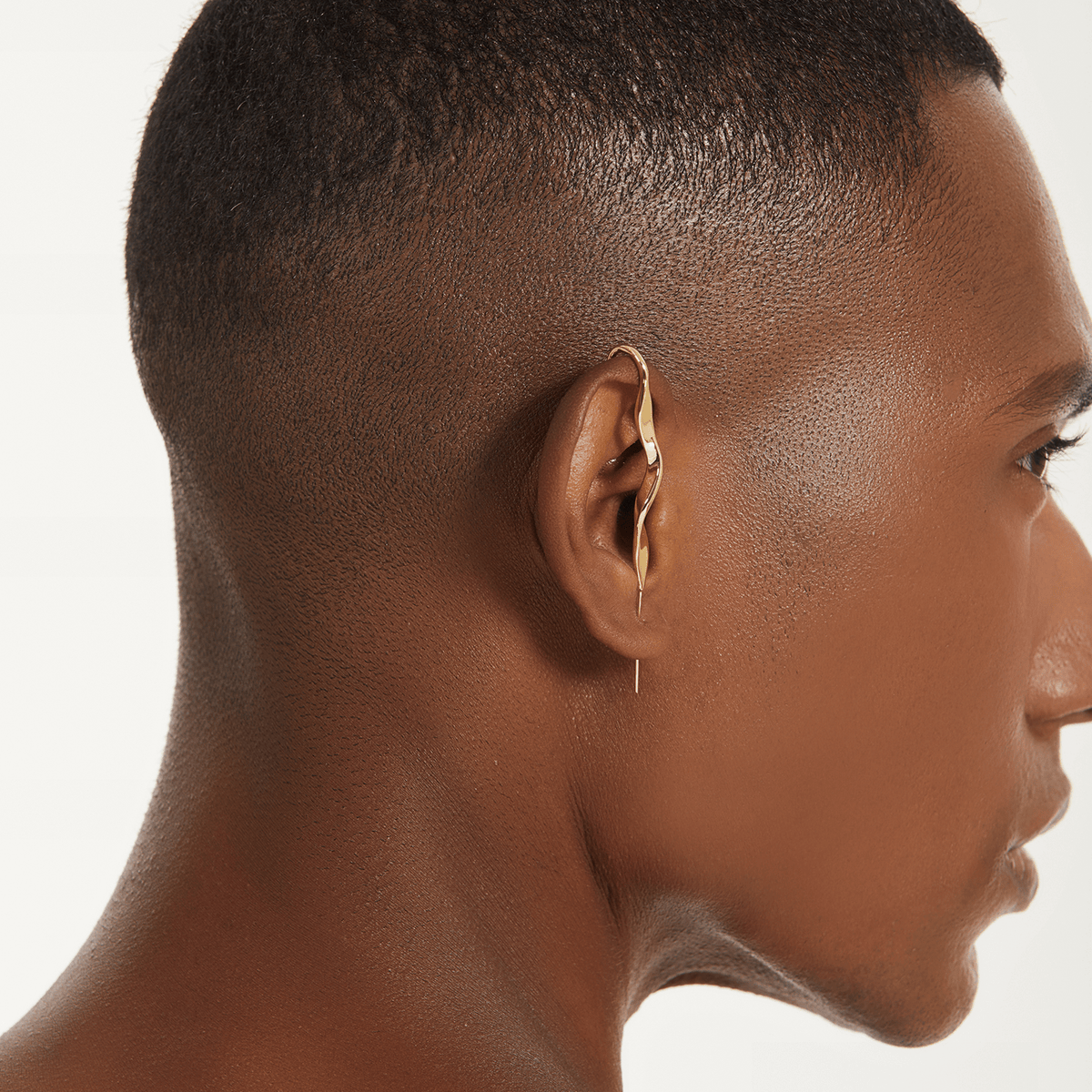 Twisted ear cuff in gold worn on the ear, profile view