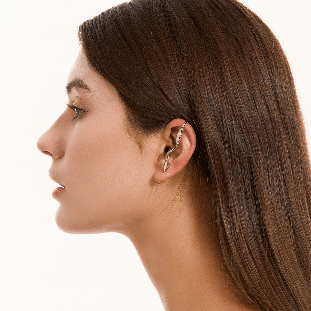 Twisted ear cuff in silver worn on the ear, profile view