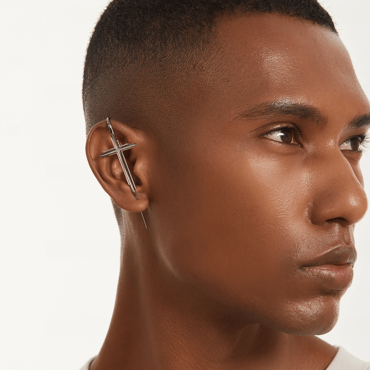 Cross ear cuff in black worn on the ear, profile view