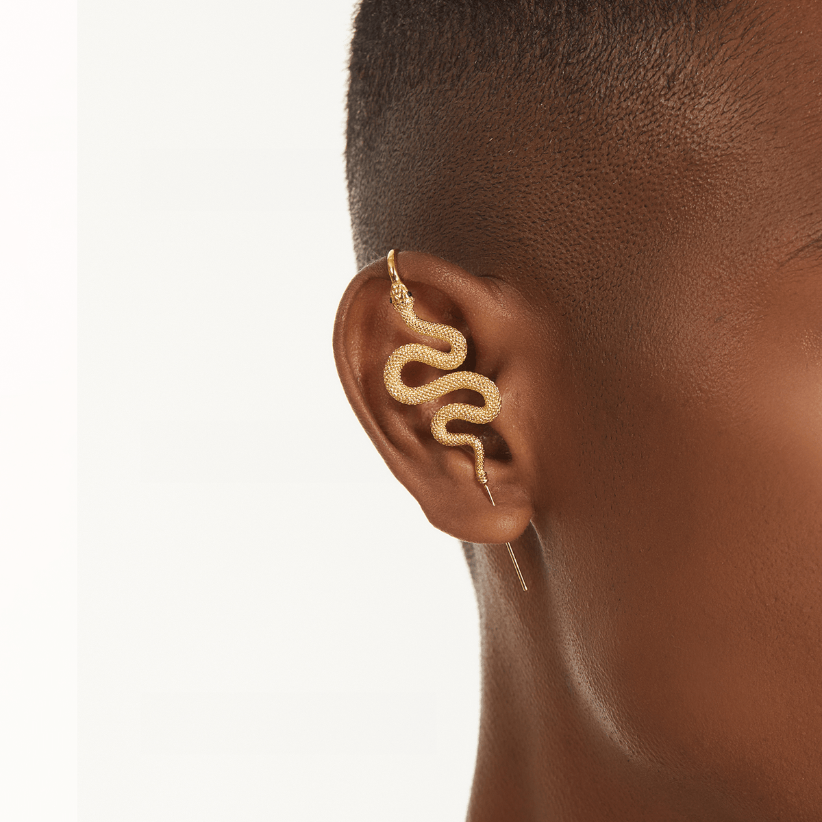 Serpent ear cuff in gold worn on the ear, profile view