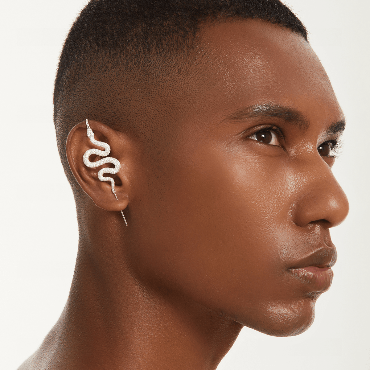Serpent ear cuff in silver worn on the ear, profile view