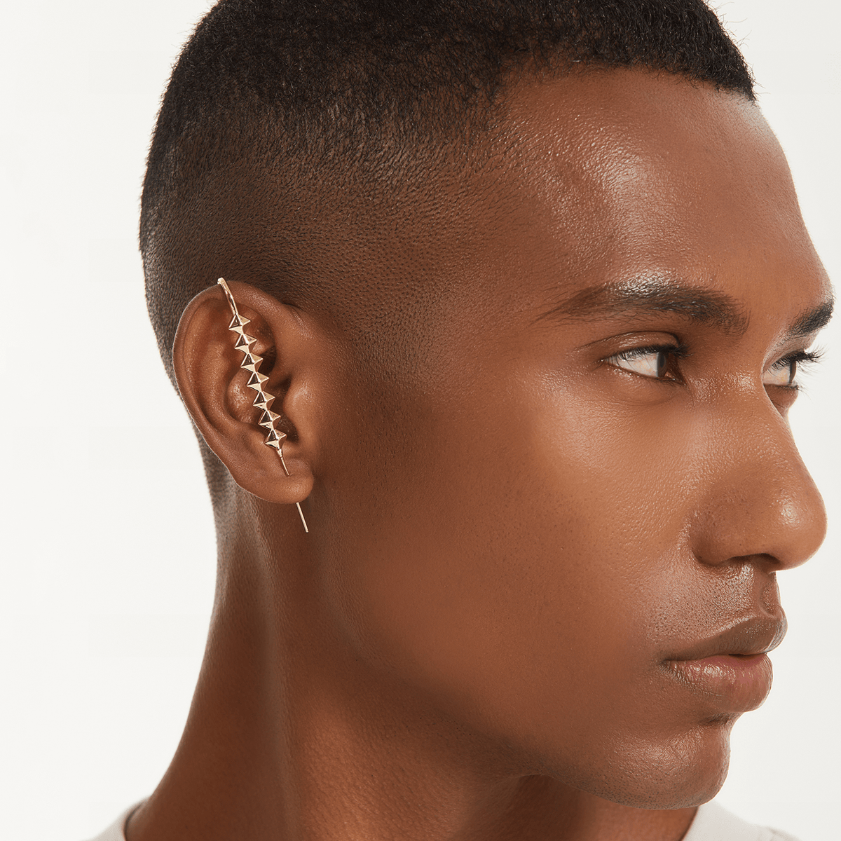 Studded ear cuff in gold worn on the ear, profile view