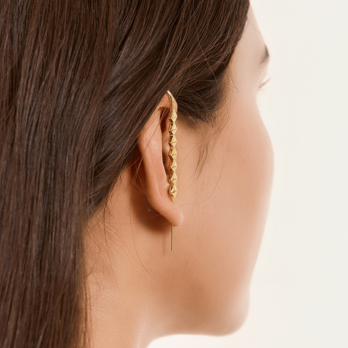 Studded ear cuff in gold worn on the ear, profile view